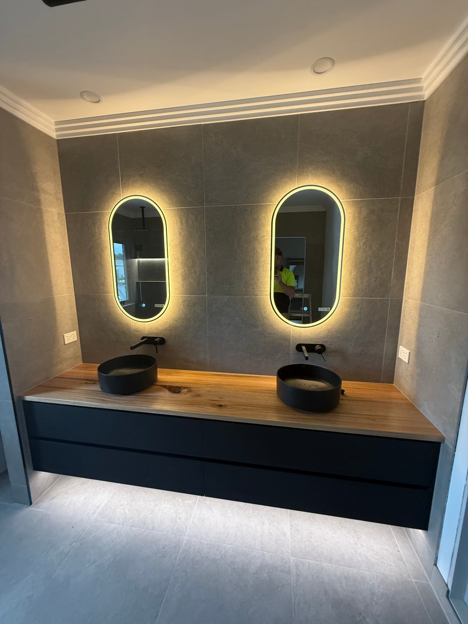 Renovated bathroom with backlit mirrors and timber-top floating vanity