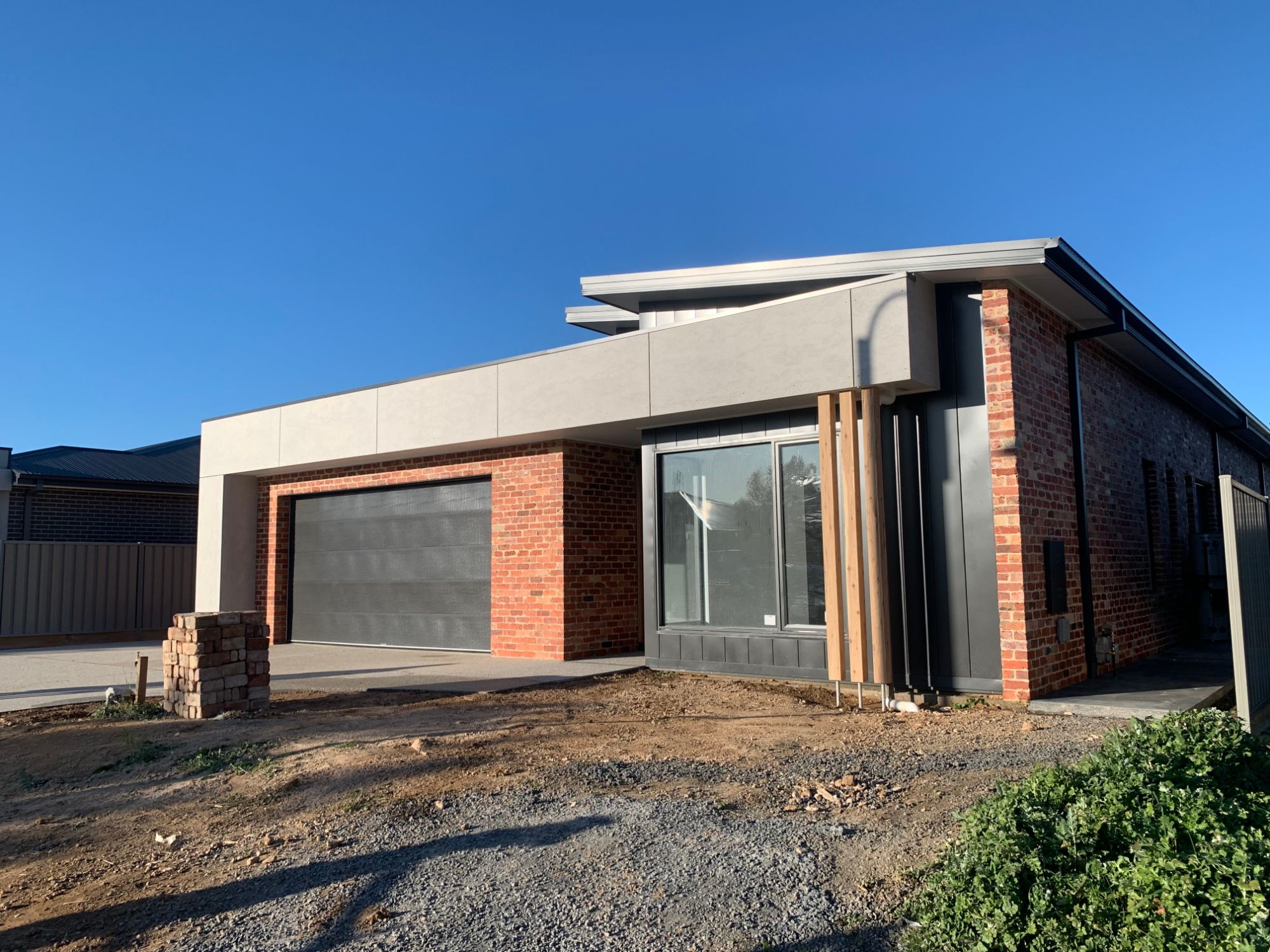 Modern home with recycled red brick, render panels and timber battens