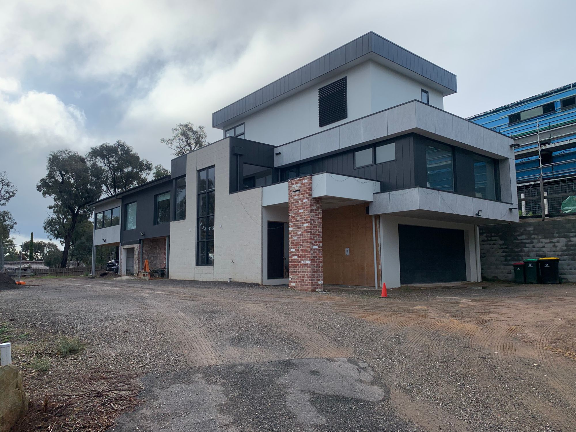 Three-storey extension and renovation with cantilevered upper level, brick pier and mixed cladding