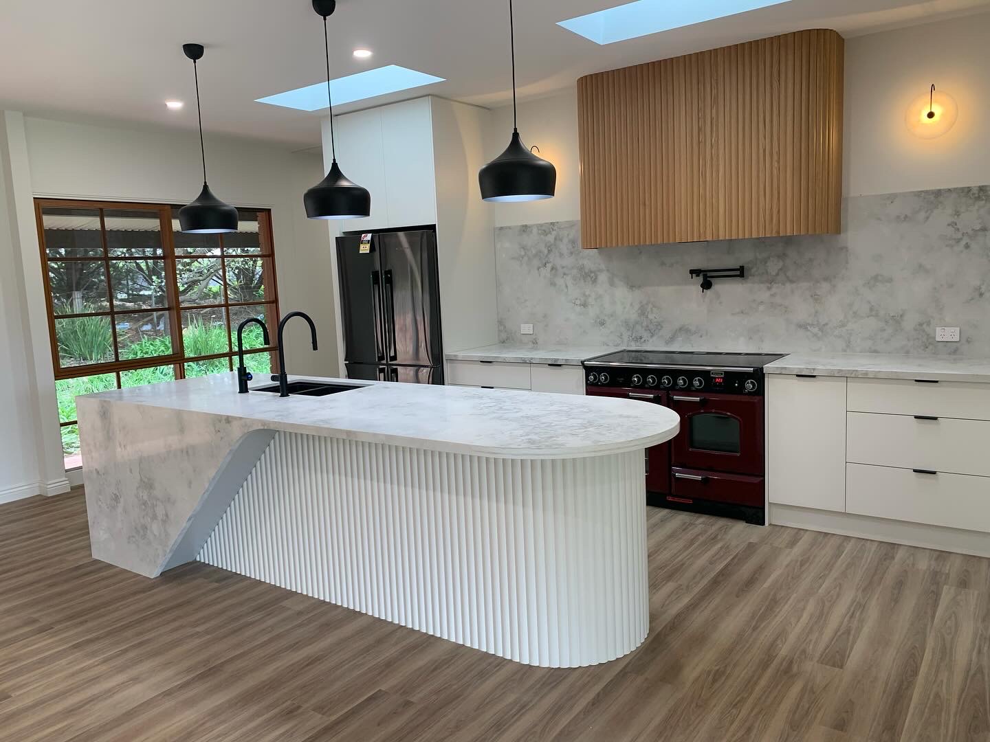 Renovated kitchen with curved fluted island and timber rangehood